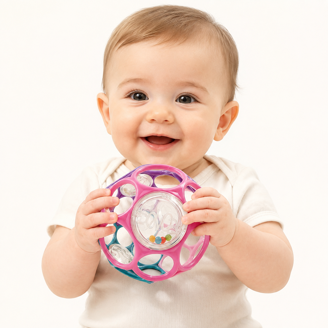 Baby holding a colorful toy with a plain background